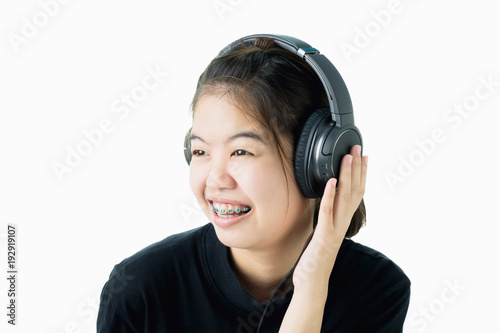 Asian girl in black casual dress listening to music from black headphones. In a comfortable and good mood, on a white background gives a soft light.