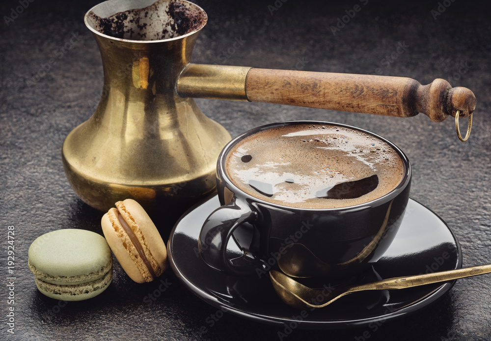 Cup of coffee, coffee maker (turka) with wooden handle, macaroons on dark  surface. Stock-Foto | Adobe Stock