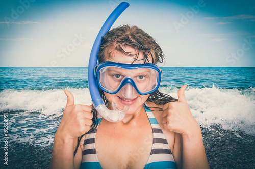 Woman with snorkeling mask for diving stands near the sea