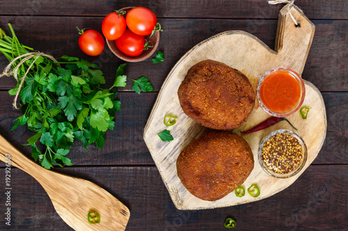 Large juicy cutlets stuffed with boiled egg on a cutting board on a dark wooden background. Scottish cutlet. The top view