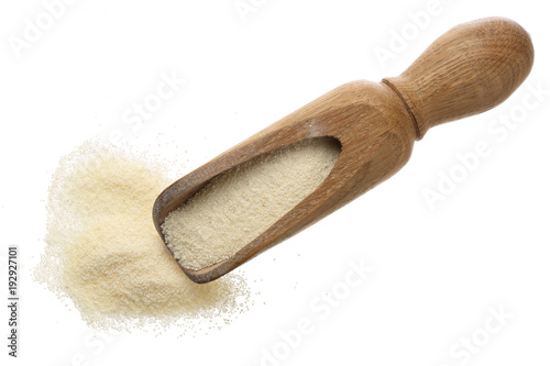 raw semolina in wooden scoop isolated on white background. Top view