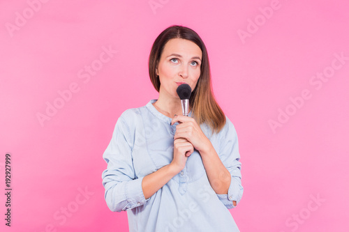 Professional makeup artist with brushes on pink background