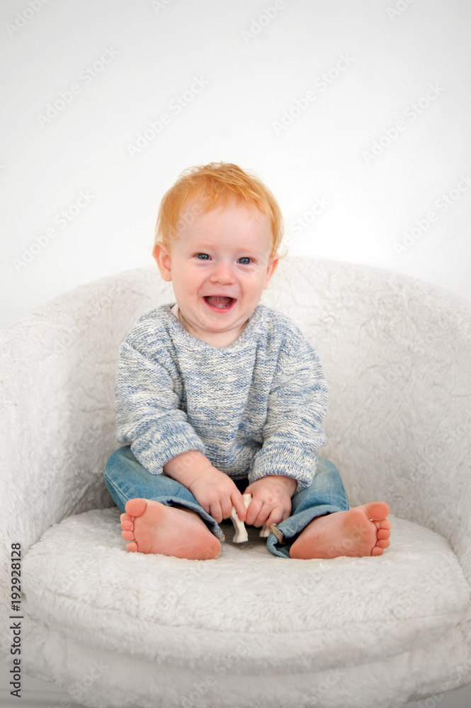 Fototapeta premium Kid sits on a white plush armchair