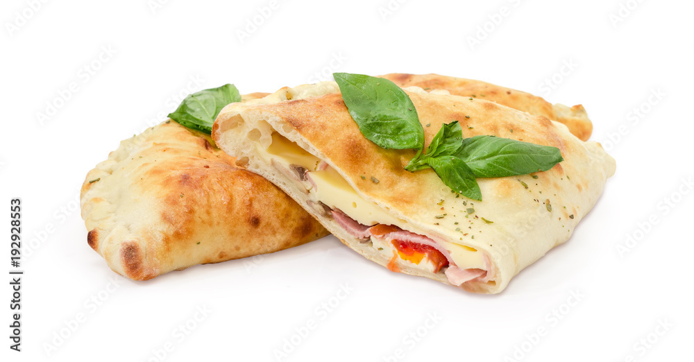 One whole and half of baked calzone with basil twigs