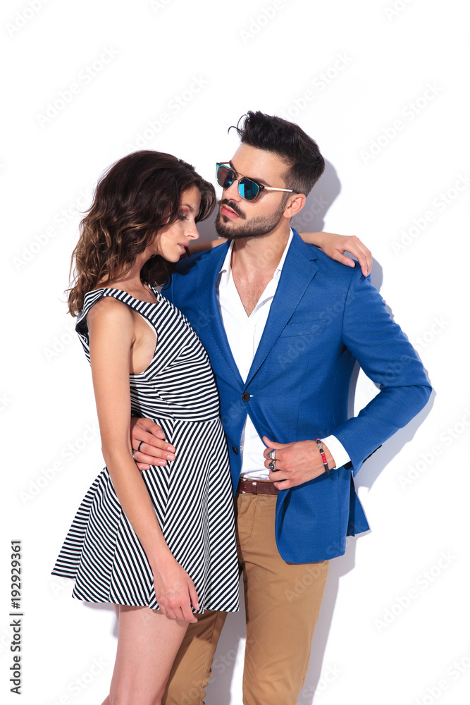 Naklejka premium man in sunglasses pulls coat while embracing his woman