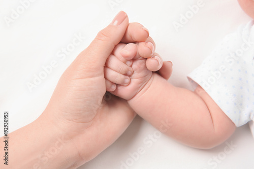 Mother holding newborn baby's hand on white background, closeup