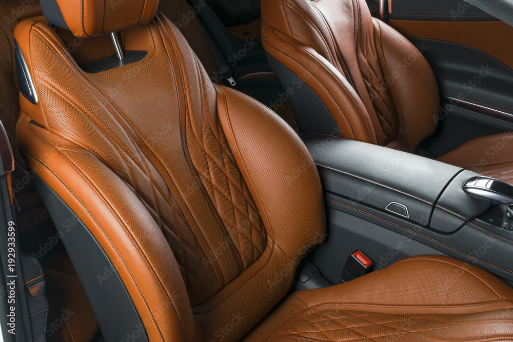 Modern Luxury car inside. Interior of prestige modern car. Comfortable leather brown seats. Orange perforated leather cockpit with isolated Black background. Modern car interior details
