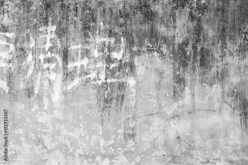 Weathered and aged concrete wall texture background with some faded Chinese writing in black and white.