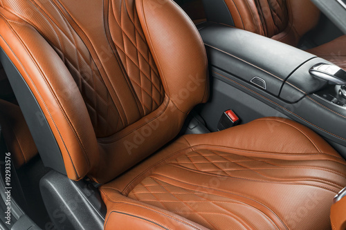 Modern Luxury car inside. Interior of prestige modern car. Comfortable leather brown seats. Orange perforated leather cockpit with isolated Black background. Modern car interior details © Aleksei