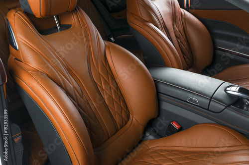 Modern Luxury car inside. Interior of prestige modern car. Comfortable leather brown seats. Orange perforated leather cockpit with isolated Black background. Modern car interior details © Aleksei