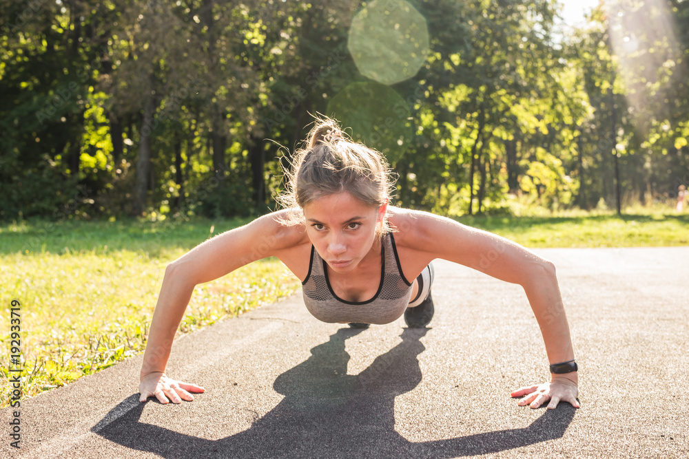Young fit woman exercising by doing push-ups outdoors Young fit woman exercising by doing push-ups outdoors