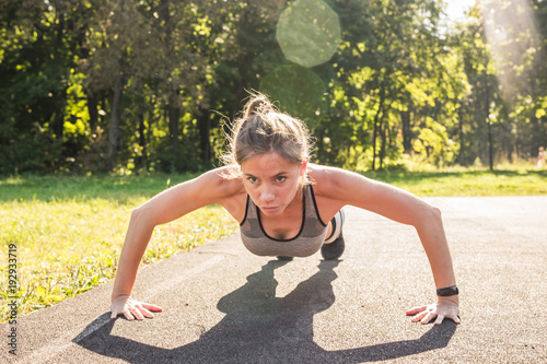 Young fit woman exercising by doing push-ups outdoors