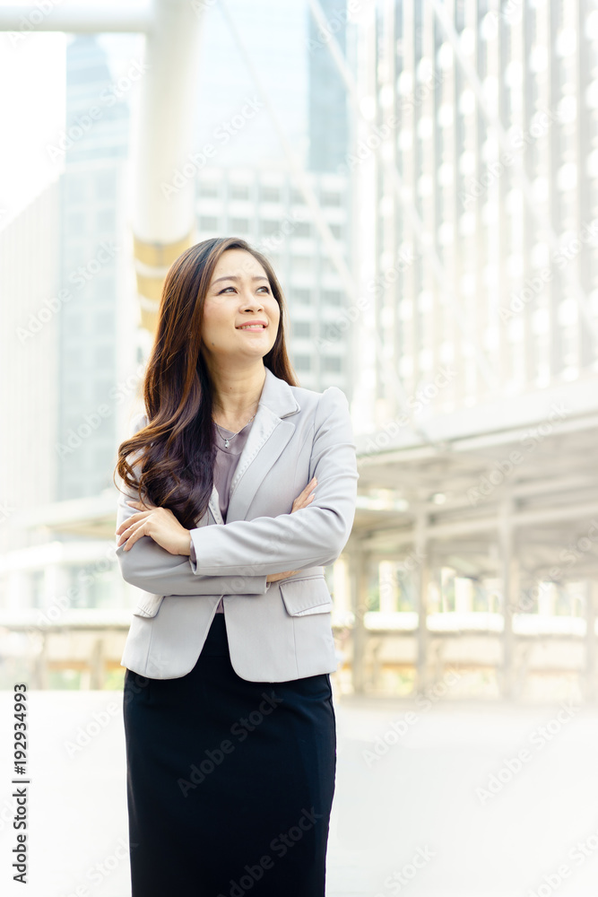 Confident smiling businesswoman with crossed arms in the city. Ways to be happy at work concept
