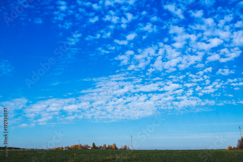 Blue sky with clouds and meadow with yellow grass