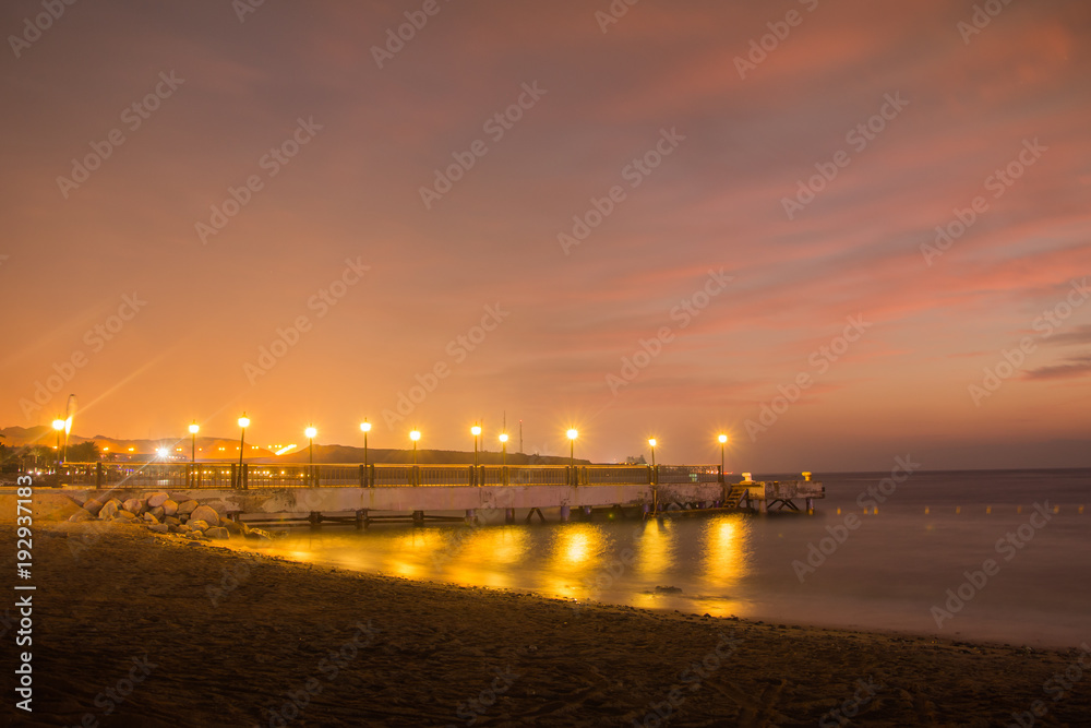 Sea and pier with lanterns in a night