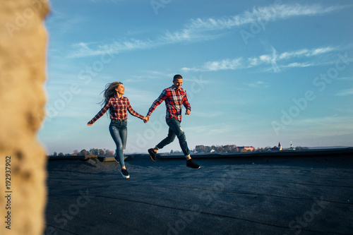 The lovely couple in love running along roof