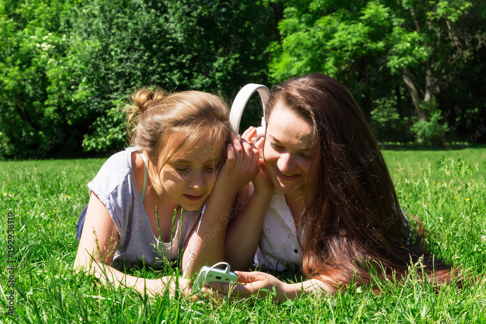Two girls spending time together in city park. Listen music by smart phone. Two girls spending time together in city park. Listen music by smart phone.