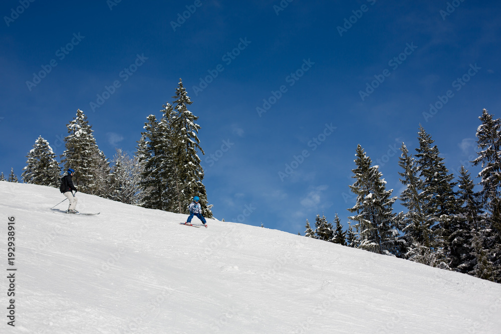 Father and son, dad and child, skiing together in Austrian resort
