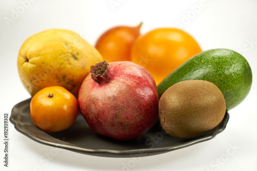 Owoce egzotyczne - granat, papaja, mango i inne na metalowym talerzy, na białym tle 
