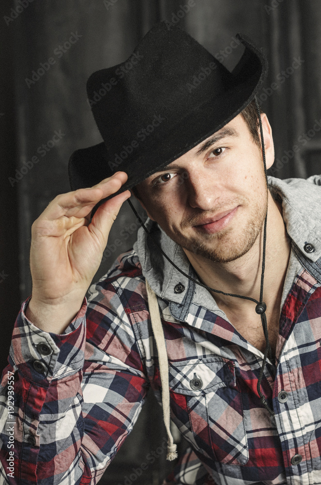 Portrait of a Cowboy. dark hair, jeans , plaid shirt.