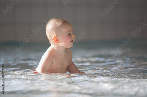 Fototapeta Naklejka Na Ścianę i Meble -  Little cute baby boy, swimming happily in a shallow pool water