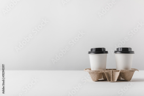 two coffee in paper cups in cardboard tray on table