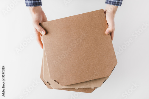 cropped image of courier holding pizza boxes in hands isolated on white © LIGHTFIELD STUDIOS