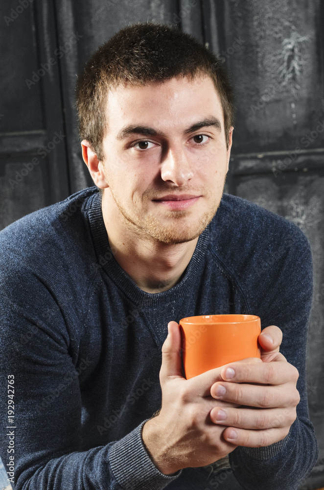 holding the orange Cup. Portrait of a man , dark hair. holding the orange Cup. Portrait of a man , dark hair.