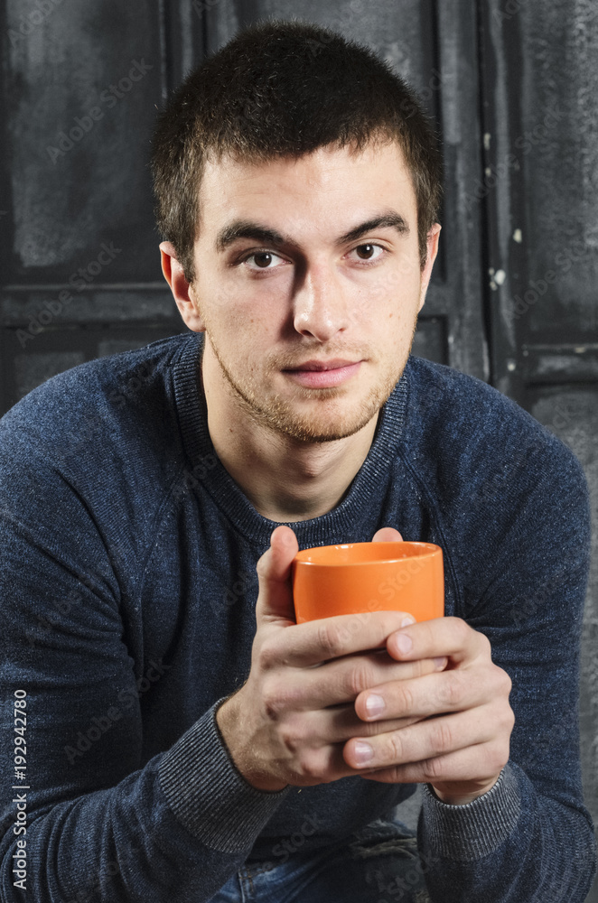 holding the orange Cup. Portrait of a man , dark hair. holding the orange Cup. Portrait of a man , dark hair.