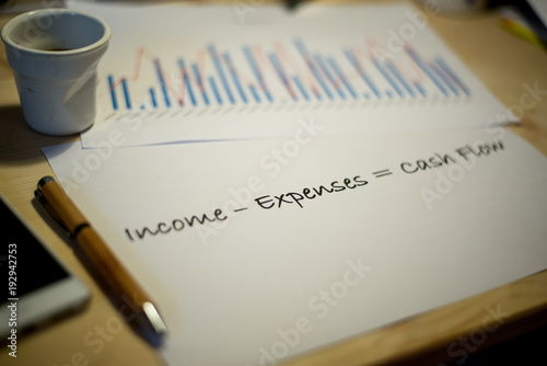 Photography Cash flow statement printed on a white sheet of paper and business charts on a m