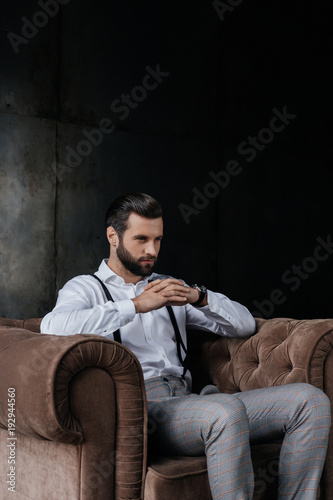 handsome pensive man sitting in armchair