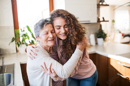 A teenage girl with grandmother at home, hugging. photo