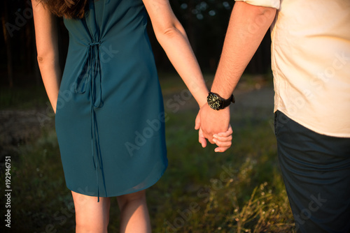 Loving couple holding hands at sunset. Forest.