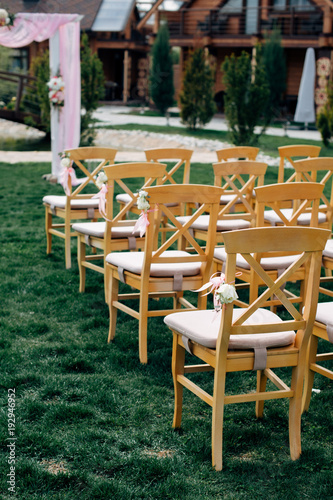 Open air wedding ceremony, wooden chairs in row on the grass