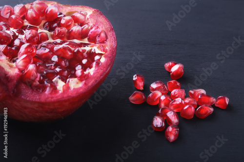 Pomegranate seeds and Beautiful ripe pomegranate on black mirror background with place for copy space. photo
