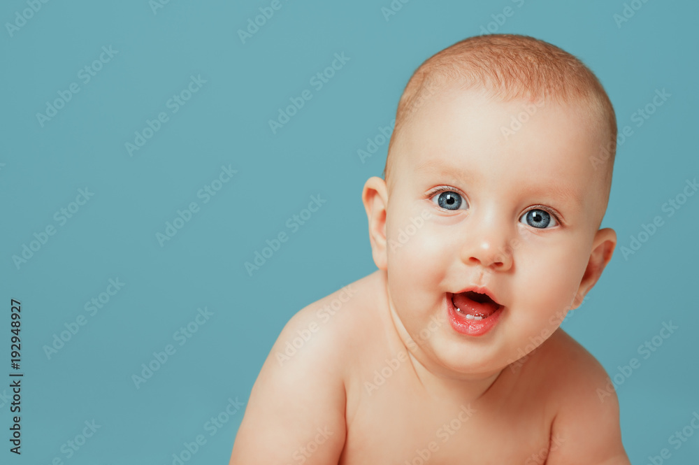Close-up portrait of adorable newborn baby smiling on isolated blue background. People Lifestyle Family Kids Emotions concept. Sweet infant in bedroom looking to cam. Close-up portrait of adorable newborn baby smiling on isolated blue background. People Lifestyle Family Kids Emotions concept. Sweet infant in bedroom looking to cam.
