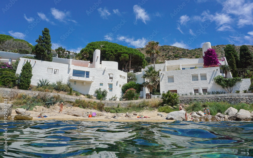 Waterfront houses on the Mediterranean sea shore with sand and rocks, Spain on the Costa Brava, Catalonia, Canyelles Petites, Roses, Girona, seen from water surface