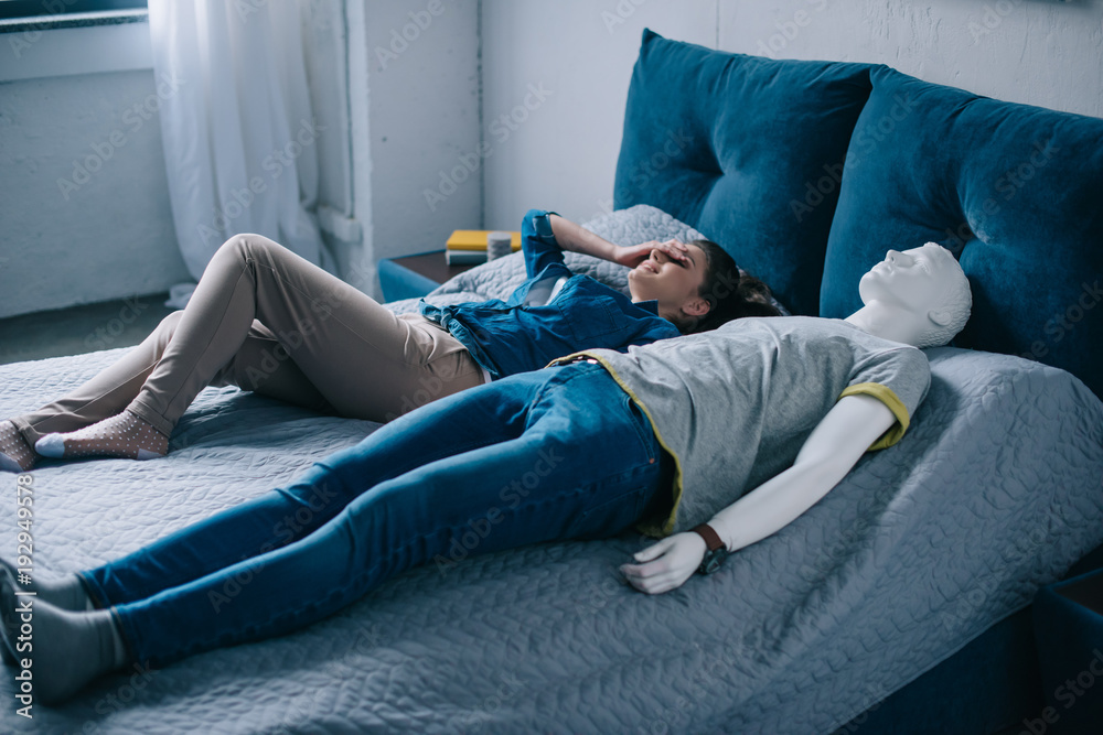 young woman lying in bed with mannequin, perfect relationship dream