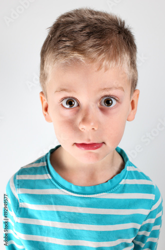 Young boy with wide open eyes and blue striped shirt
