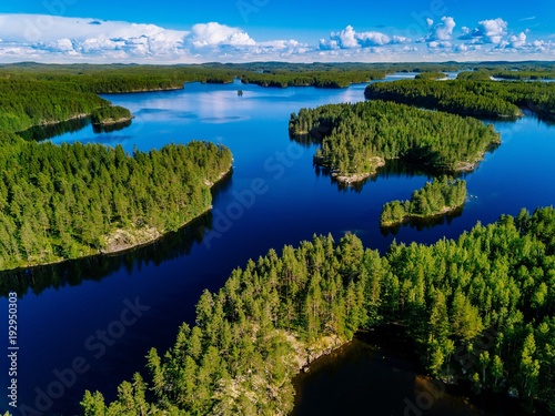 Aerial view of blue lakes and green forests on a sunny summer day in Finland.