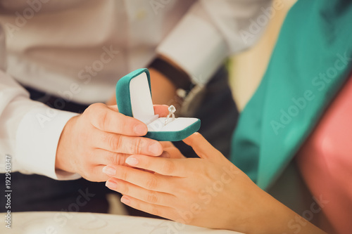 Young man makes a marriage proposal to his girlfriend and surprises her with a beautiful engagement ring. Closeup