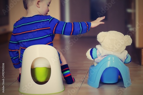 Little boy is training on a potty with his buddy. Vintage style. photo