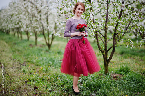 Portrait of a beautiful bridesmaid posing with bride's wedding bouquet in blossoming garden.