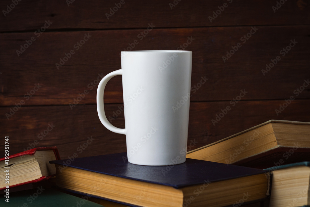 White Cup With Hot Coffee on Deployed Books on a Dark Wooden Background White Cup With Hot Coffee on Deployed Books on a Dark Wooden Background