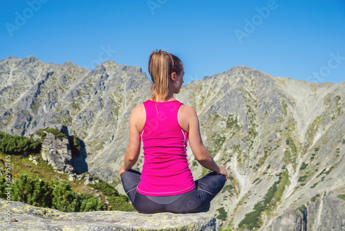 young woman meditate on top of the mountain