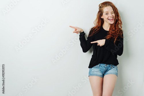 Laughing young woman pointing to copy space