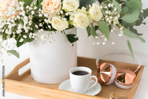 Blush wedding bouquet with roses, baby's breath and eucaluptus in wooden tray with coffee and hedphones