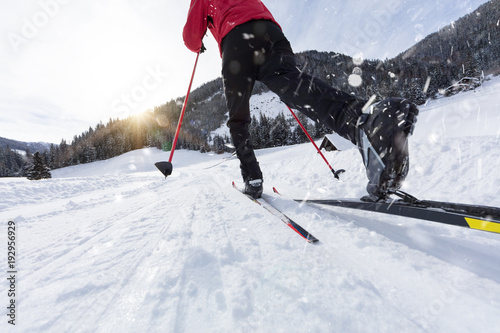 Man cross-country skiing during sunny winter day.