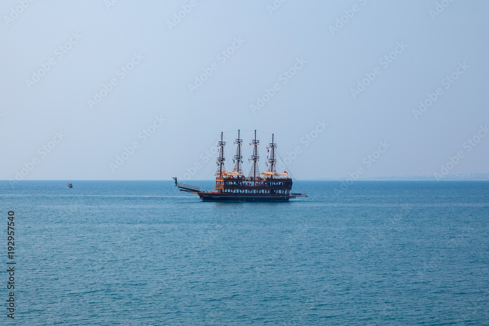pirate ship sails in blue sea. Concept rest in black and Mediterranean Sea
