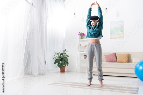 girl doing yoga with virtual reality headset on yoga mat at home